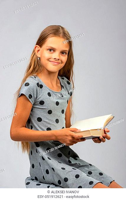 A girl of ten years distracted from reading a book and happily looked into the frame