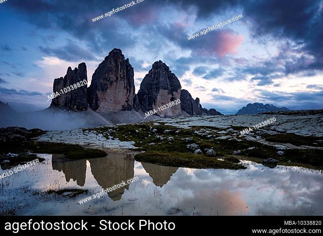 Drei Zinnen, Sesto Dolomites, South Tyrol, Italy, mountain range of the three peaks reflected in puddle after rain showers