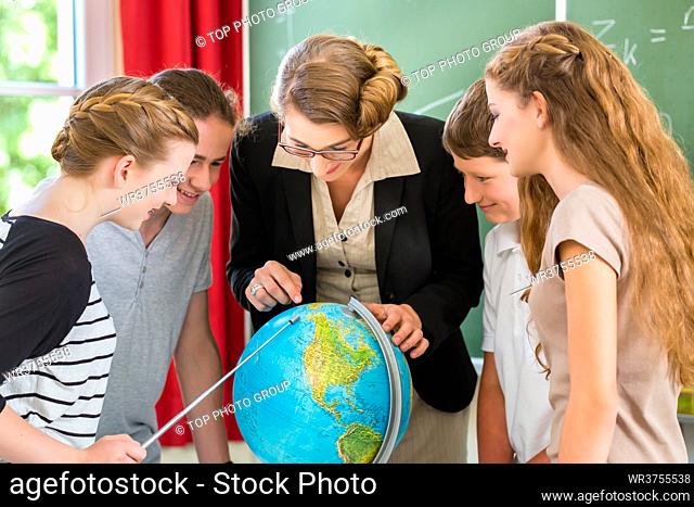 Students or pupils having group work while geography lesson and the teacher test or educate them in school or class