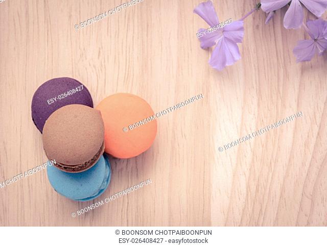 French pink macarons with blue flower on wooden background. Retro-Vintage filter effect