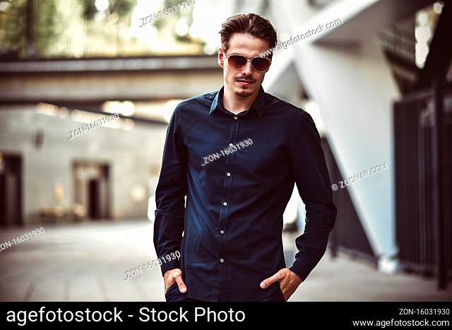 Young stylish and confident happy handsome businessman model in shirt lifestyle in the street in sunglasses