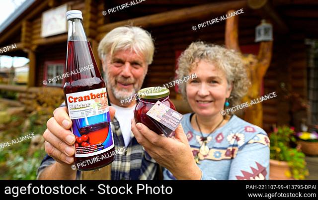 PRODUCTION - 26 October 2022, Lower Saxony, Gilten: Wilhelm and Sonja Dierking hold cranberry juice from their own harvest in their hands