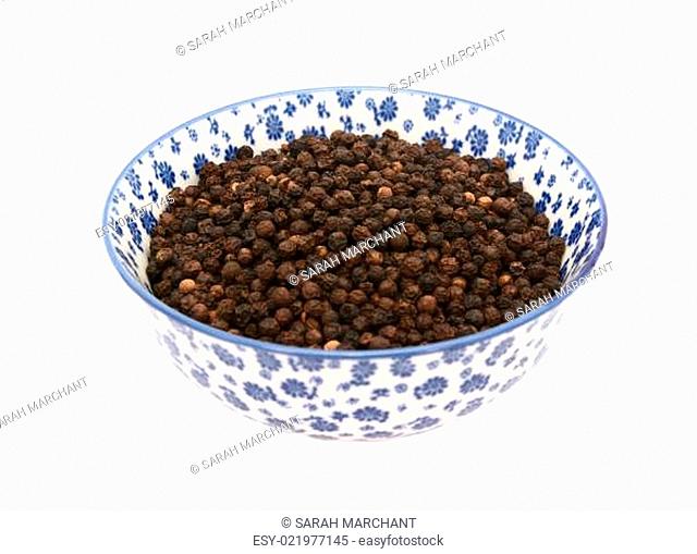 Black peppercorns in a blue and white china bowl