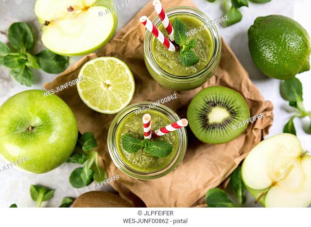 Two glasses of green smoothie and ingredients