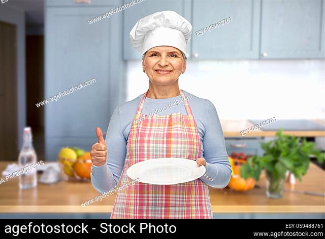 smiling senior woman or chef holding empty plate