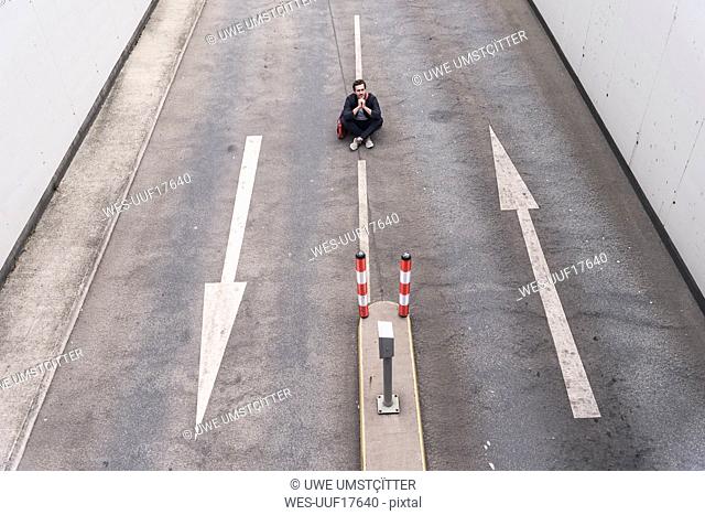 Businessman sitting on road with arrow signs