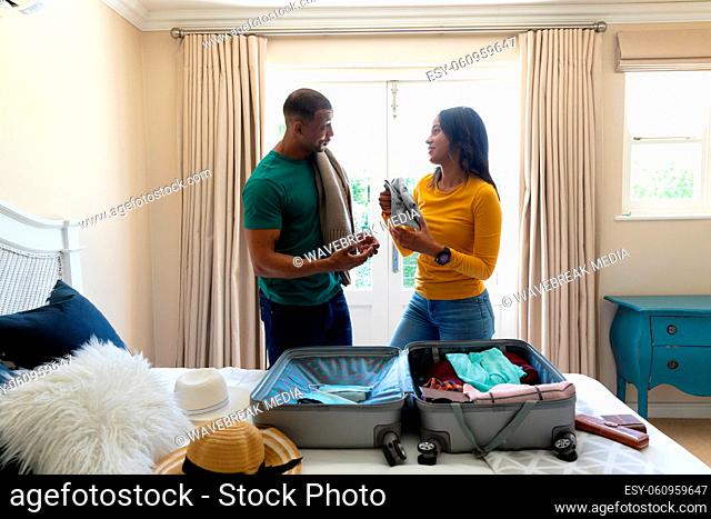 African american young couple talking while packing luggage in bedroom at home