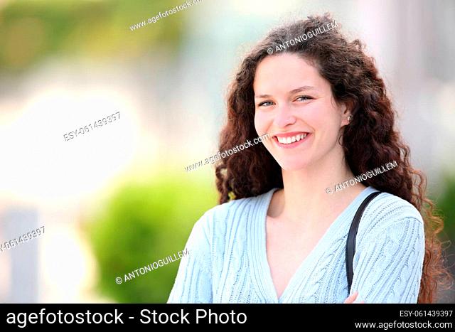 Portrait of a happy woman with curly hair standing in the street