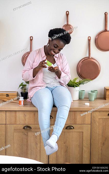 Healthcare. African woman sitting on the table with pills in hands