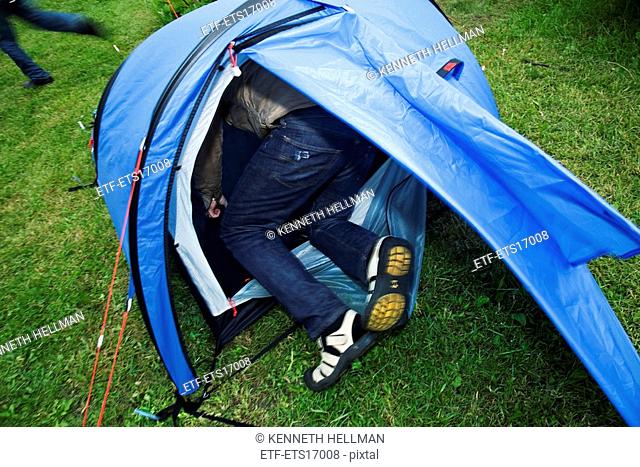 Man trying to get into a small tent, Sweden