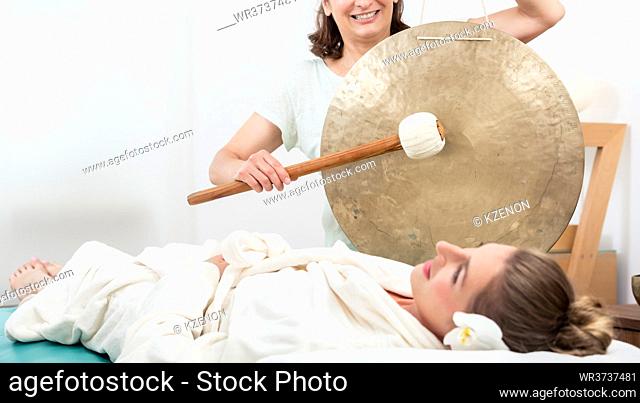 Smiling woman relaxing in spa while masseuse making sound