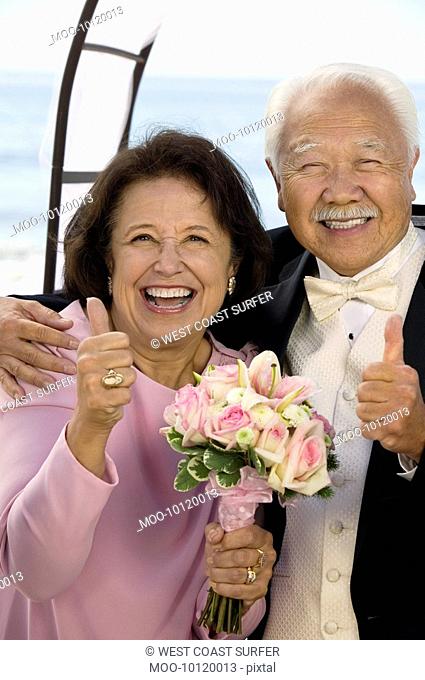 Couple at wedding giving thumbs-up smiling portrait