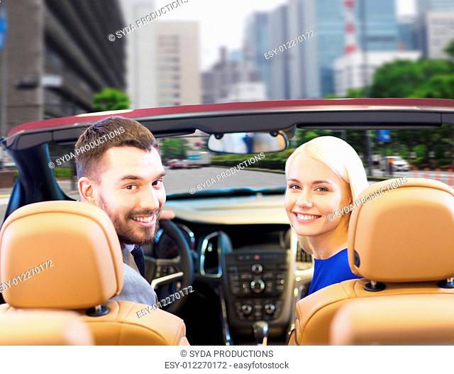 drive, auto transport and people concept - close up of happy couple driving in cabriolet car from back over city street background