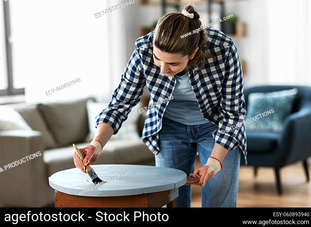 woman painting old wooden table with grey color
