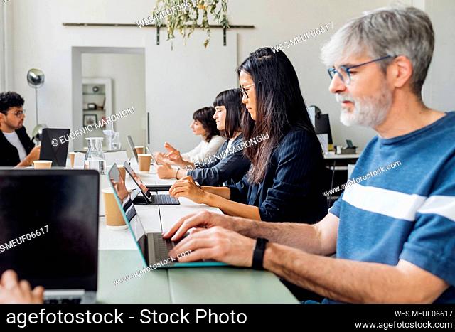 Multiracial business people working on laptop at desk in office