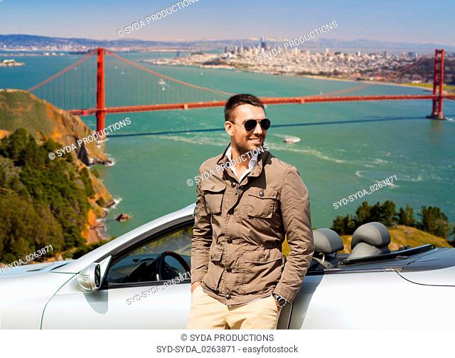 man at convertible car over golden gate bridge