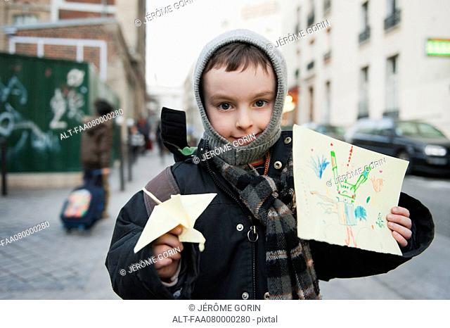 Boy showing his drawing and origami crane