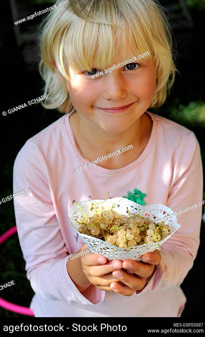 Portrait of a little girl holding freshly picked currants