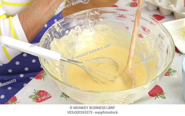 Close up of senior woman breaking egg into bowl and then whisking into mixture.Shot on Canon 5D Mk2 at at a frame rate of 30 fps