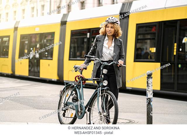 Woman with bicycle commuting in the city, Berlin, Germany