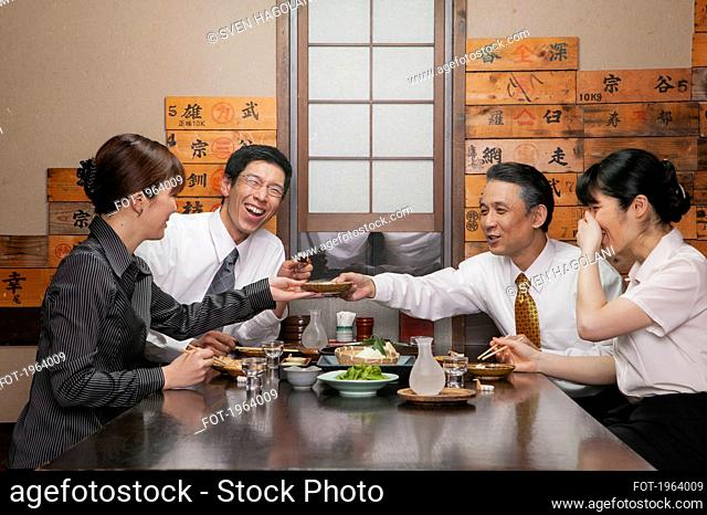 Happy Japanese business people enjoying sushi lunch in restaurant