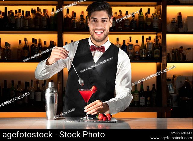 Young barman serving a cocktail at night club. High quality photo