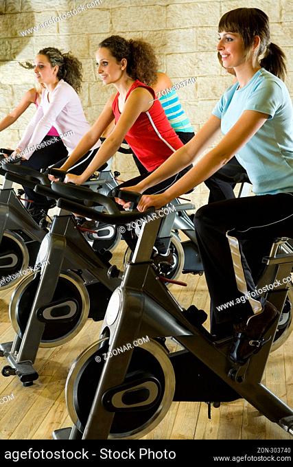 The group of women training on exercise bikes at the gym. Side view