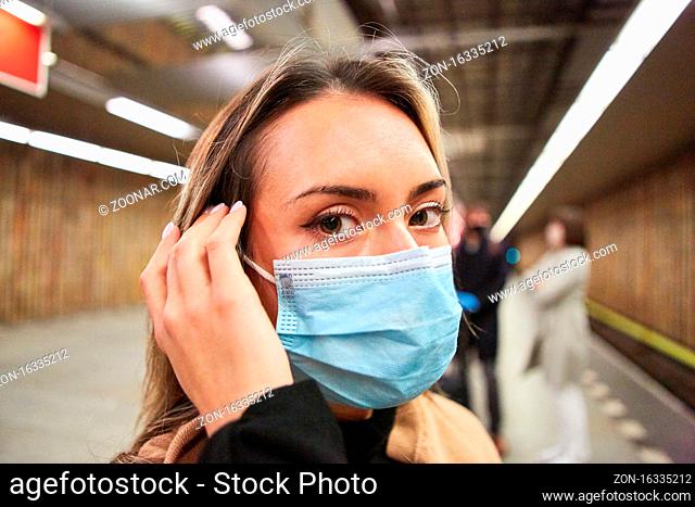 Frau als Fahrgast oder Pendler mit Mundschutz wegen Covid-19 Pandemie im ÖPNV
