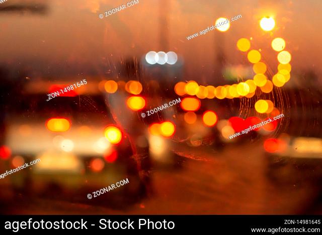 Blurry photo of an evening glowing freeway through a car window. Selective focus macro shot with shallow DOF