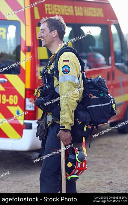 06 September 2022, Saxony-Anhalt, Elend: Equipped with a hoe, a member of the special unit from the forest fire team returns from the forest fire area late in...