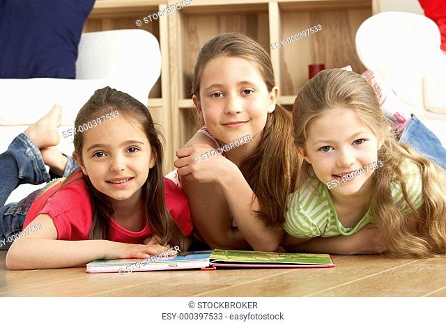 Three Young Girls Reading Book at Home