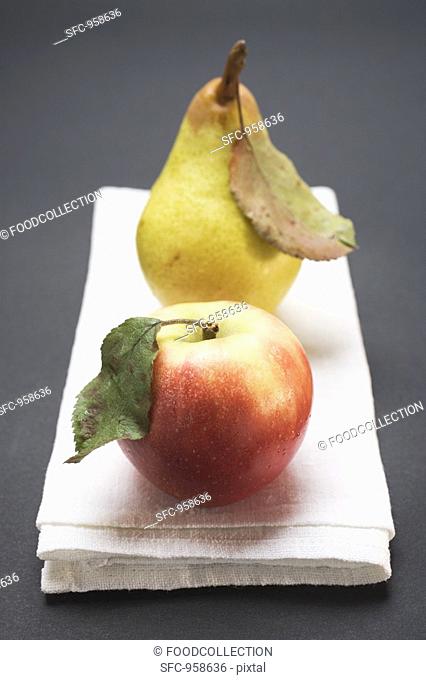 Red apple and pear with leaves on cloth