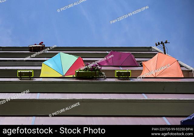 20 July 2022, Saxony-Anhalt, Halle: Residents try to keep the summer heat out of their apartments with sunshades. Glowing asphalt