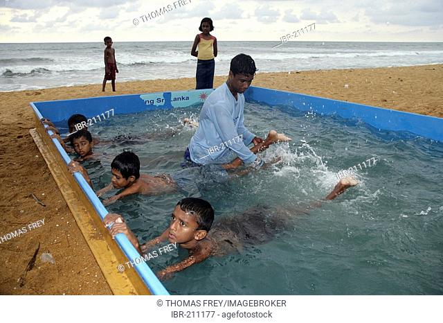 Children who have survived the Tsunami are getting familiar with the water in small pools near the ocean. Colombo, Sri Lanka