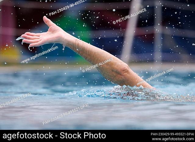 28 April 2023, North Rhine-Westphalia, Paderborn: The arm of a swimmer is seen at the Rolandsbad outdoor pool at the start of the outdoor pool season in North...