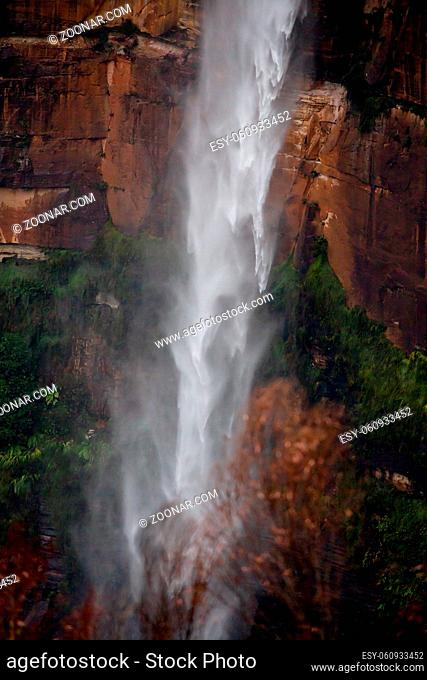Powerful waterfall tumbling over sandstone cliffs after rain, its movement patterns vary as it falls fast to the bottom