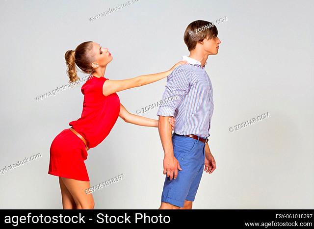 Young man leaving girlfriend. Breaking up. Over grey background