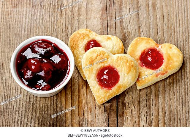 Puff pastry cookies in heart shape filled with cherries