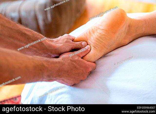 Young man having feet massage in the spa salon. Sports massage. Close-up view of masseur hands giving treating massage to his patient