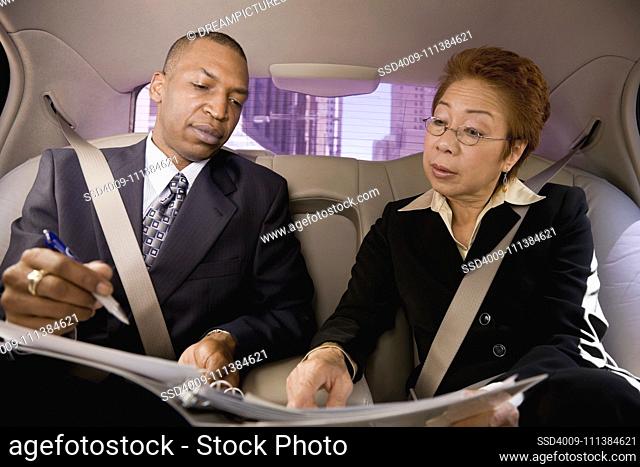 Business people working in back seat of car