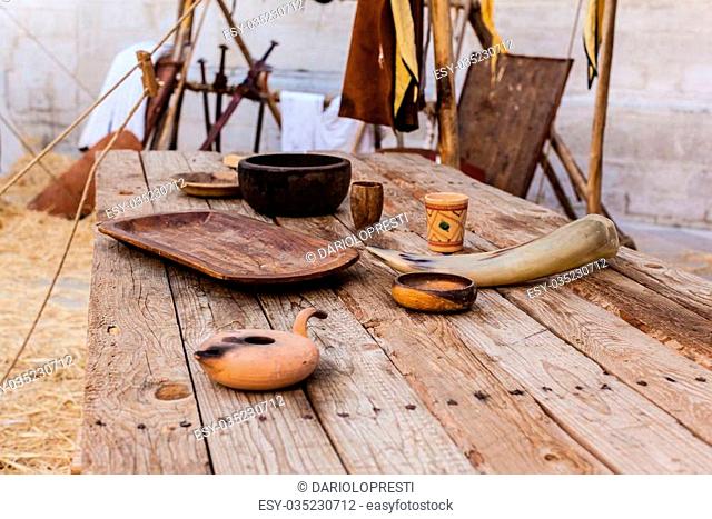 a big and old wooden table with some medieval items on it