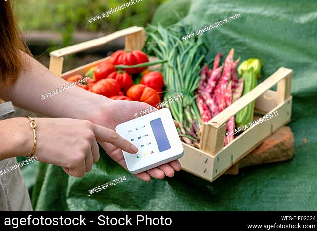 Female farmer using credit card reader in garden