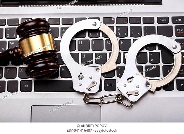 High Angle View Of Handcuffs And Gavel On Laptop Keyboard