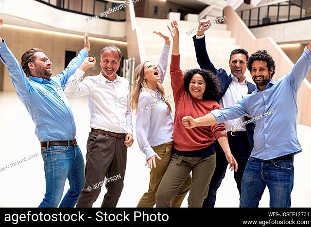 Cheerful multiracial business colleagues celebrating success in lobby
