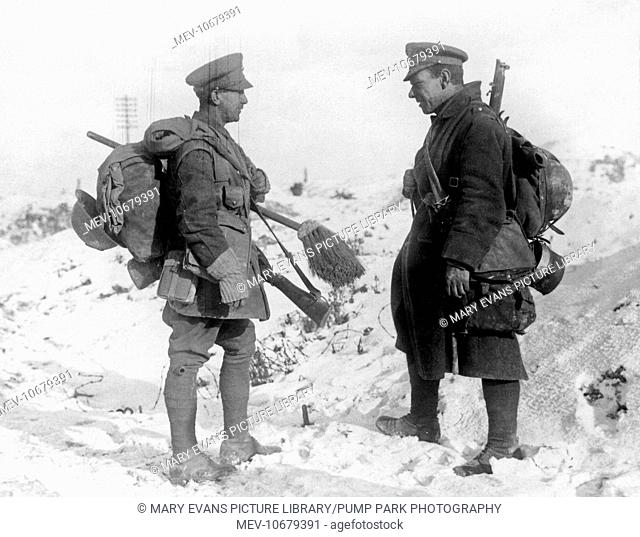 Two British soldiers have a discussion in the snow, behind the line on the Western Front during World War One