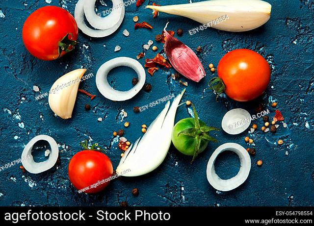 Vegetables background. Fresh vegetables (garlic, tomatoes, onions) on a dark embossed surface. View from above