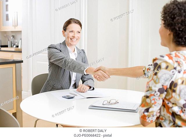 Businesswoman shaking hands with woman in dining room