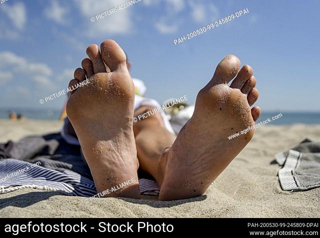30 May 2020, Schleswig-Holstein, Timmendorfer Strand: A woman is sunbathing at the Timmendorfer Strand at the Baltic Sea