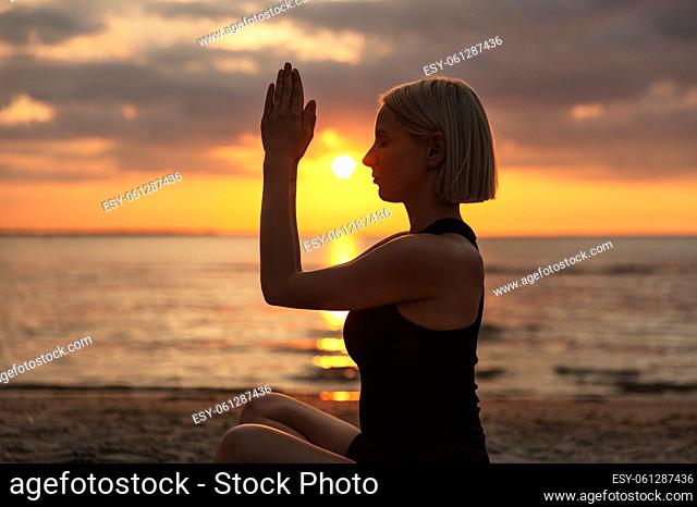 woman meditating in easy pose on beach