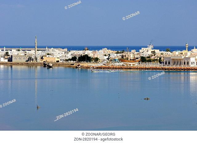 Blick über die Lagune auf die Hafenstadt Sur am Golf von Oman, Sultanat Oman / View across the blue lagoon at the harbour town Sur at the Gulf of Oman
